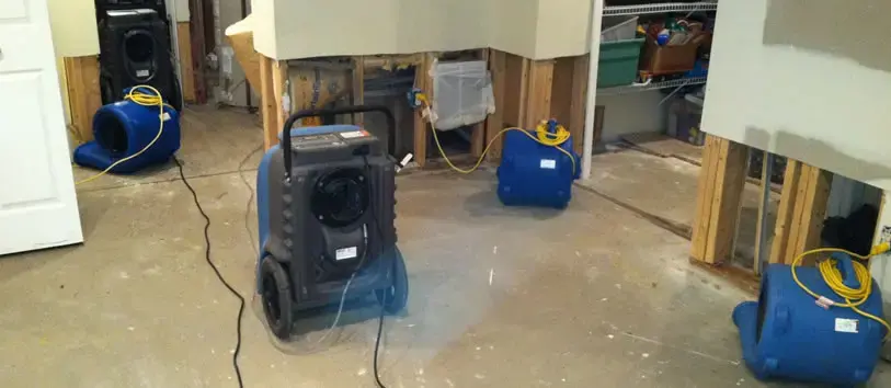 Dehumidifier and air movers drying a basement after the lower drywall was removed